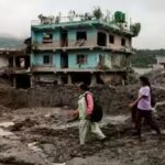 people-walk-past-damaged-houses-following-deadly-flash-floods-in-nepal.jpg